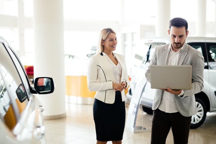 man and woman inside of a car dealership