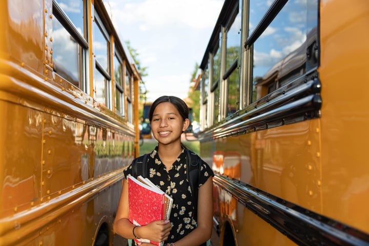 girl standing between two busses